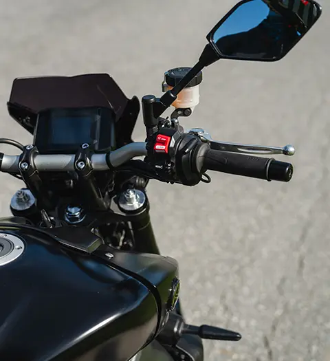 Närbild på styret och instrumentpanelen på en svart motorcykel, med en tydlig bild av handtagen